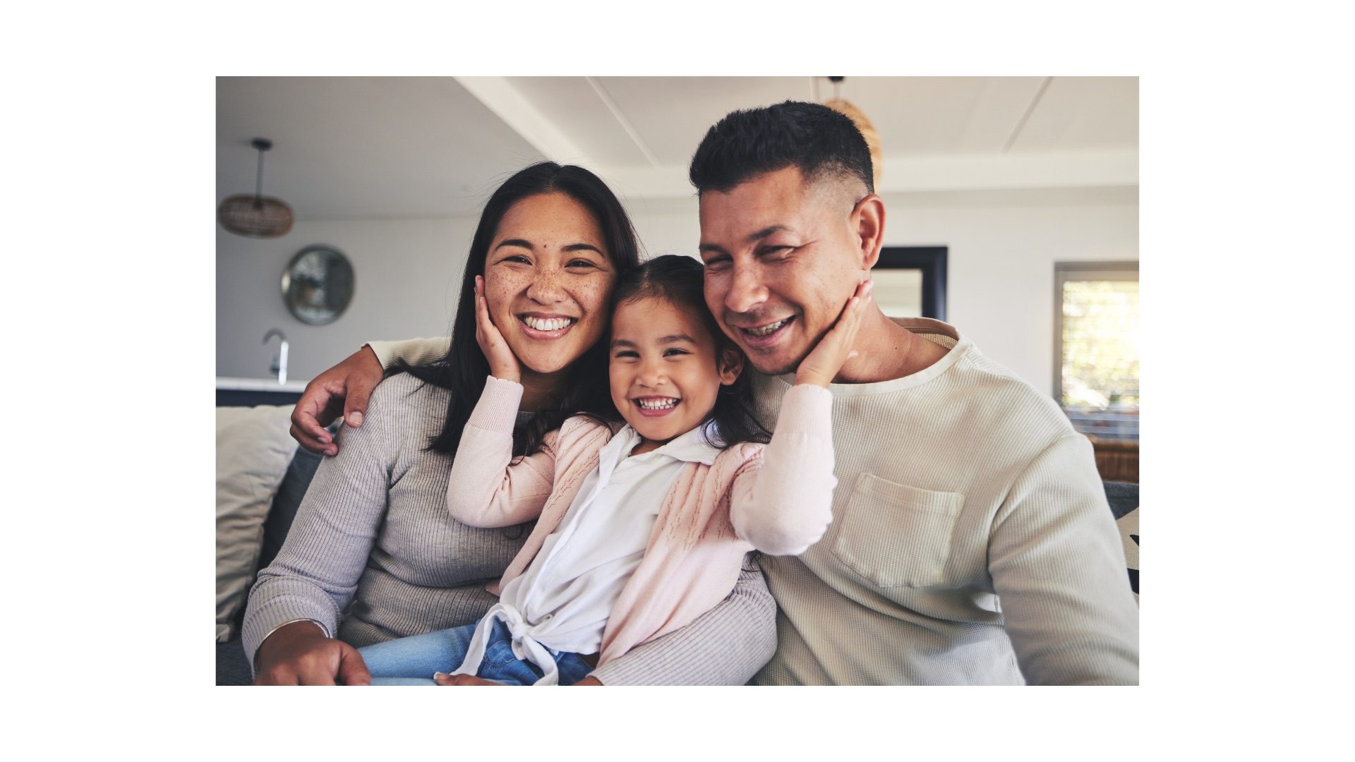 Two adults and a young child smiling together on a sofa