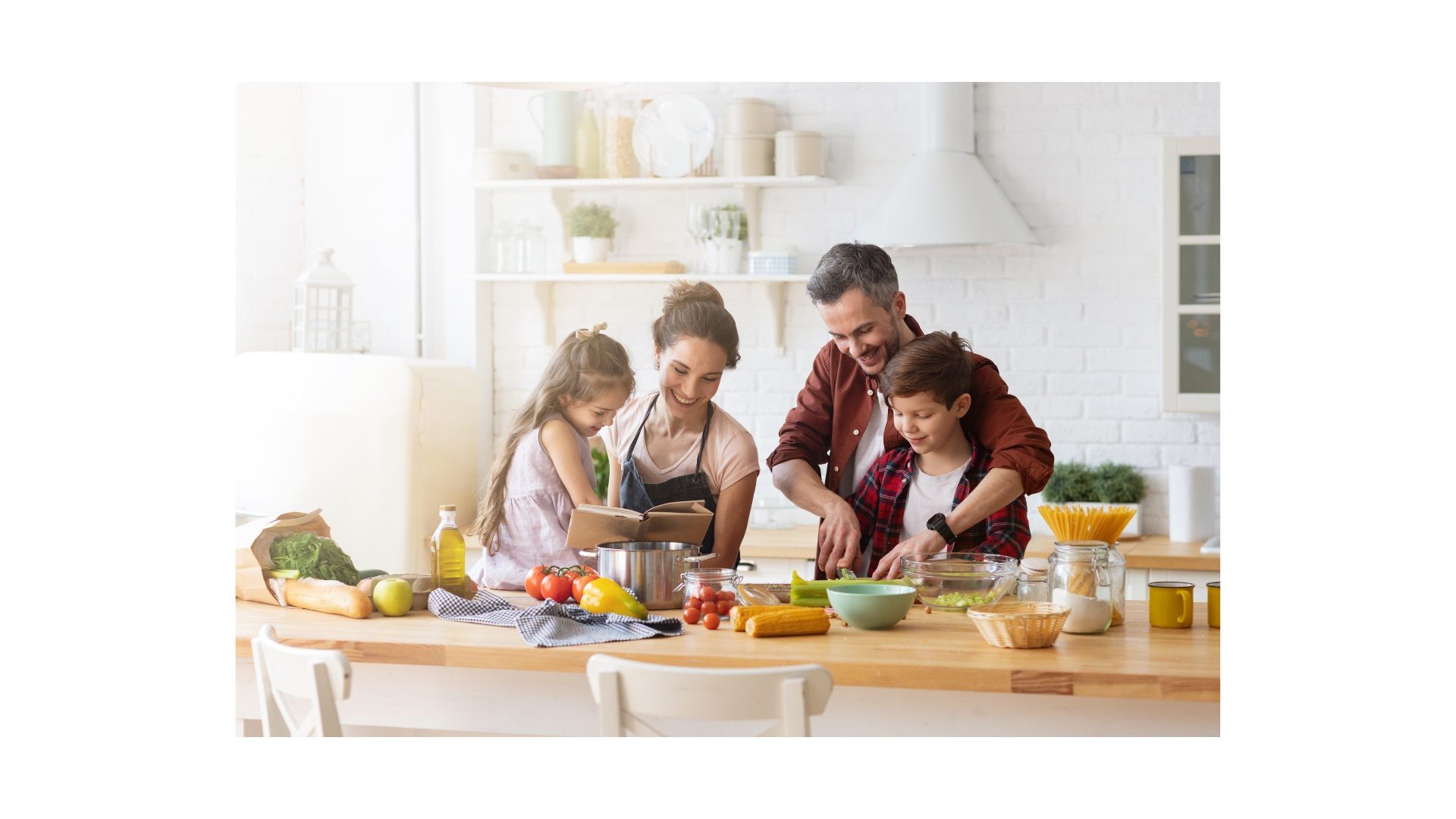 Two adults and two children preparing a meal together in a bright kitchen