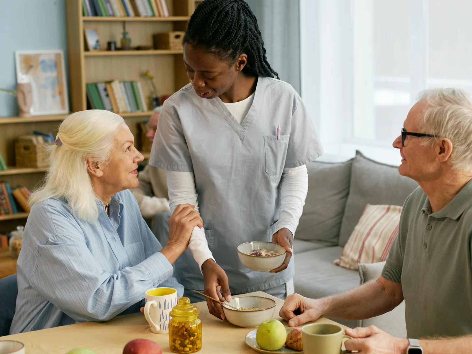 A support professional sharing a meal and conversation with older adults
