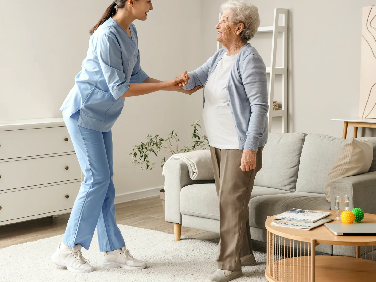 A therapist helping an older adult practice standing safely at home