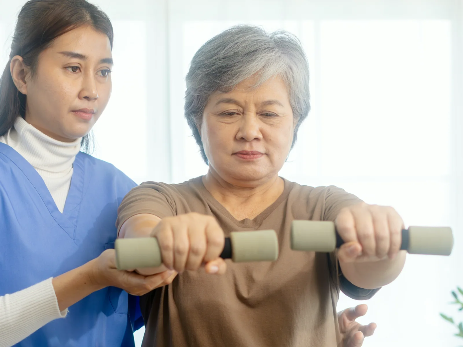 A therapist guiding an older adult through a strength exercise
